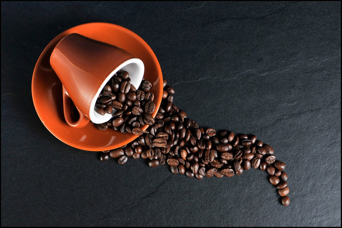 Coffee beans spilling out of an orange coffee mug